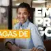 Mulher sorridente sentada à mesa com laptop e documentos em ambiente corporativo