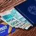 Carteira de Trabalho com notas de cem reais e cartão do PIS/Pasep sobre mesa de madeira, representando pagamento do abono salarial 2026.