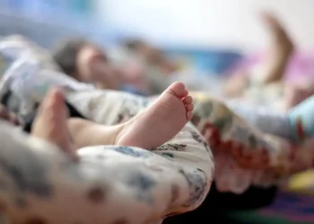 Pés de crianças deitadas em colchões cobertos por cobertores coloridos