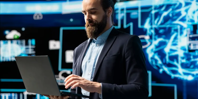 Homem de negócios com laptop em frente a gráficos de dados digitais, representando uma área de tecnologia de alta remuneração.