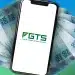 Smartphone exibindo logo do FGTS sobre leque de notas de R$ 100 em fundo azul esverdeado, representando os pagamentos do saque-aniversário do FGTS