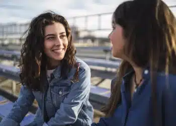Duas mulheres conversando ao ar livre com expressão segura e confiante, representando empoderamento e autenticidade.