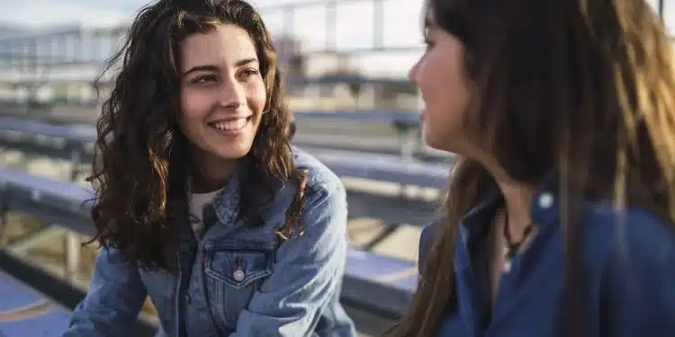 Duas mulheres conversando ao ar livre com expressão segura e confiante, representando empoderamento e autenticidade.