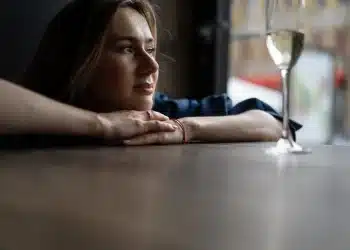 Pessoa pensativa olhando pela janela, representando a busca por um propósito de vida.