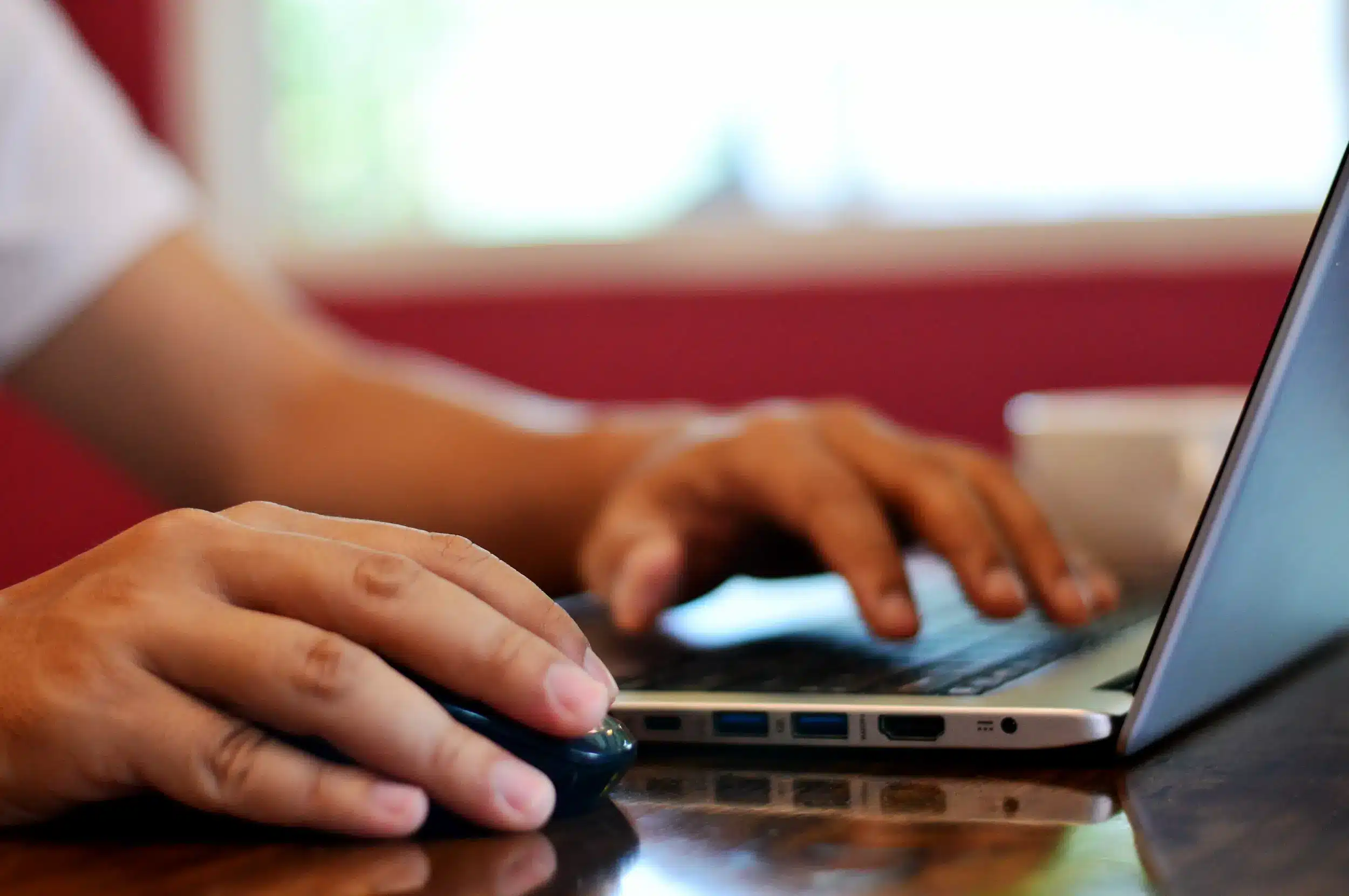 Pessoa utilizando um laptop e mouse para se inscrever em concurso público online.