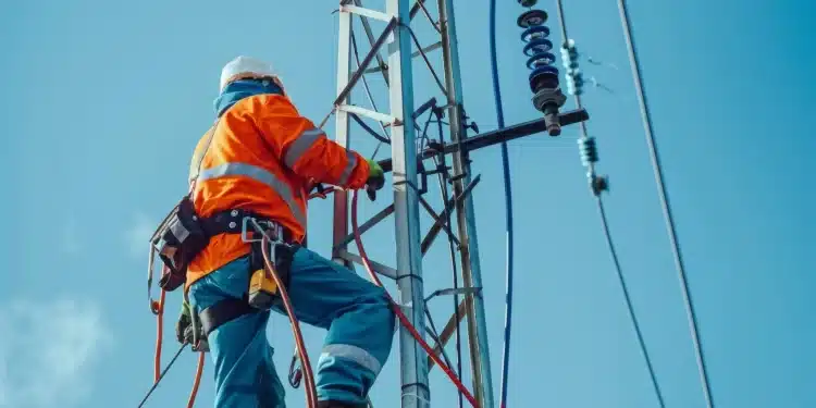 Eletricista de alta tensão trabalhando em torre de energia elétrica em grande altura
