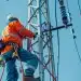 Eletricista de alta tensão trabalhando em torre de energia elétrica em grande altura