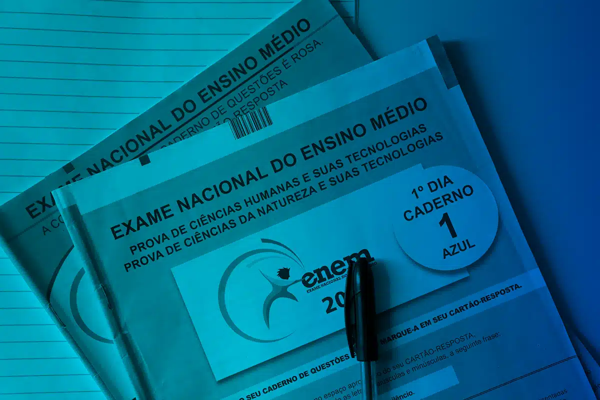 Cadernos do Enem abertos com caneta sobre as provas, representando a participação obrigatória para recebimento do Incentivo-Enem 2025.