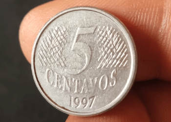 Close frontal de uma moeda prateada de 5 centavos do ano 1997, mostrando o algarismo central e a textura de linhas inclinadas ao fundo.