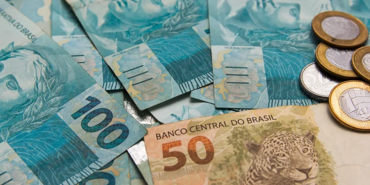 Pagamento do INSS em fevereiro com notas de real e moedas representando benefício de R$ 8.475,55.