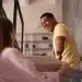 Pessoa sorrindo e ajudando outra a carregar uma caixa, representando gentileza e felicidade.