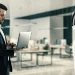 Profissional utilizando notebook diante de robô humanoide em escritório moderno, representando a colaboração entre inteligência artificial e habilidades humanas no mercado de trabalho.