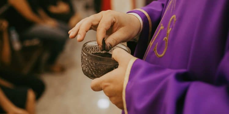 Sacerdote aplicando cinzas em pessoa na Quarta-feira de Cinzas, tradição religiosa da Igreja Católica.