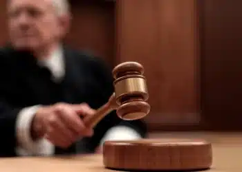Mão de juiz bate martelo na mesa em tribunal de madeira
