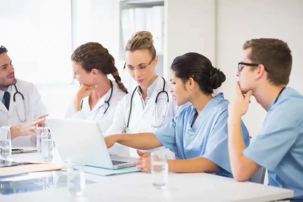 Grupo de estudantes de medicina analisando informações acadêmicas em notebook durante atividade universitária.