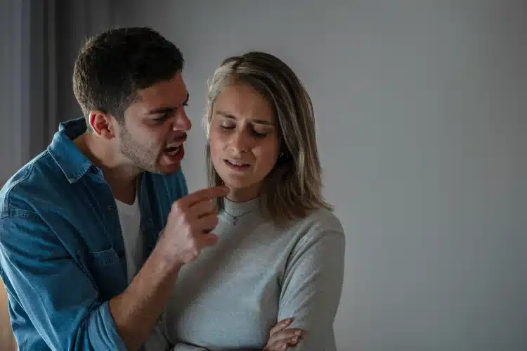 Homem gesticulando e gritando enquanto mulher expressa tristeza com braços cruzados