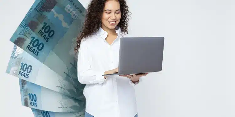 : Mulher sorridente usando notebook com várias cédulas de 100 reais ao fundo