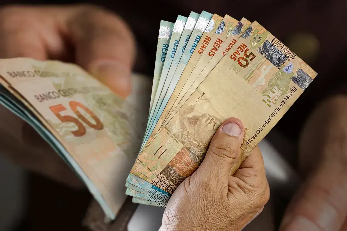Notas de real nas mãos representam o pagamento do seguro-desemprego a trabalhadores demitidos sem justa causa em 2026.
