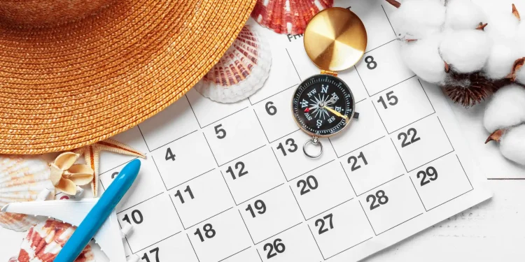 Calendário com chapéu de verão, bússola e miniatura de avião representando planejamento do feriado da Sexta-feira da Paixão 2026.