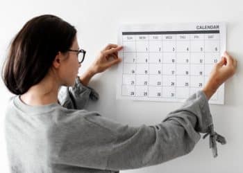 Mulher observando calendário na parede.