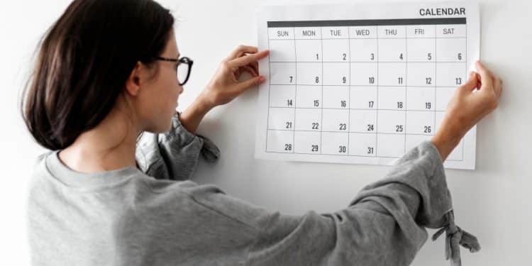 Mulher observando calendário na parede.