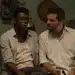 Cena do filme Marighella mostrando dois militantes reunidos em ambiente clandestino durante a ditadura militar brasileira.