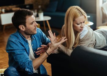 Casal discutindo na sala de casa, demonstrando tensão emocional causada por falhas na comunicação.