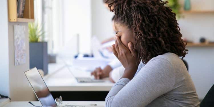 Mulher com expressão de cansaço no trabalho, simbolizando os efeitos da depressão nas profissões brasileiras em 2026.