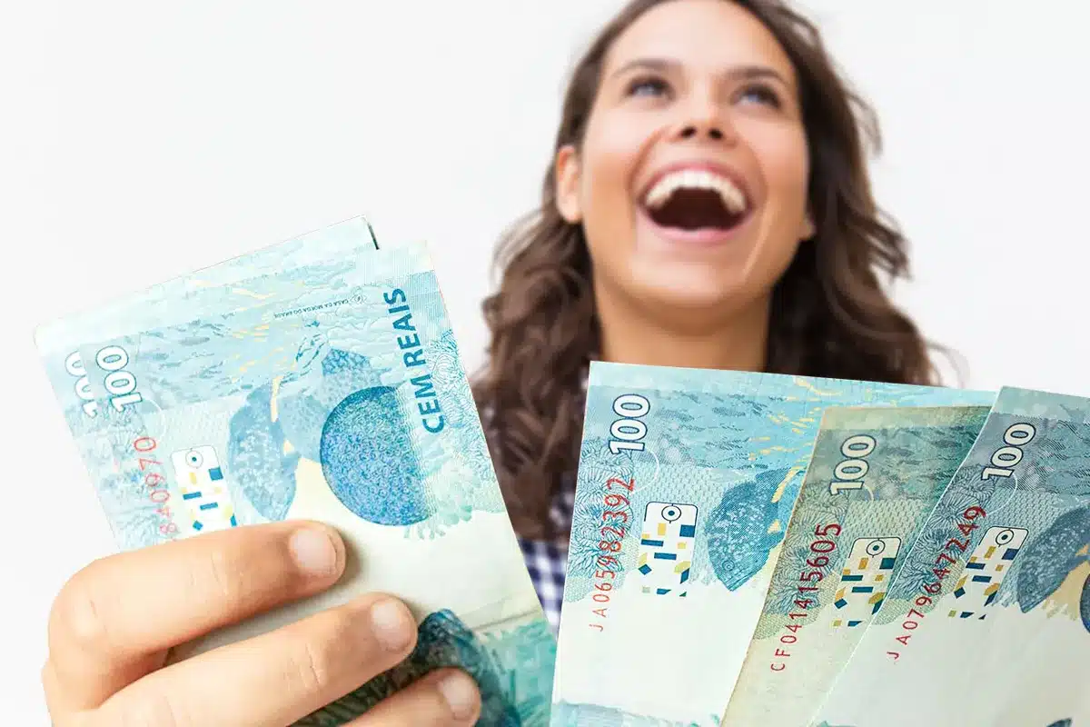 Mulher sorrindo e segurando dinheiro.