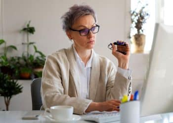 Profissional com mais de 50 anos trabalhando como autônoma no computador em escritório doméstico.