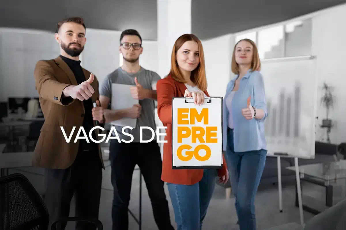 Grupo de pessoas em escritório mostrando sinal de positivo e cartaz de vagas de emprego.