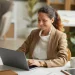 Profissional trabalhando no laptop em escritório moderno, representando os desafios e barreiras enfrentados por mulheres no crescimento da carreira.