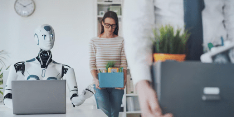 Robô humanoide trabalhando em notebook enquanto funcionários humanos carregam caixas de pertences ao sair do escritório