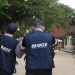 Dois recenseadores do IBGE de costas caminhando por rua com coletes azuis do Instituto Brasileiro de Geografia e Estatística