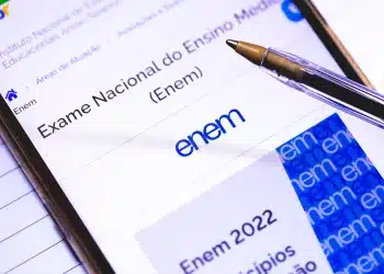 Smartphone exibindo a página oficial do Enem no portal Gov.br, com uma caneta esferográfica apoiada sobre a tela, simbolizando o planejamento de estudos para o vestibular.