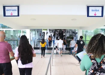 Candidatos entrando em local de prova com placas de entrada e saída visíveis representando o dia de aplicação das provas do concurso do IBGE 2026