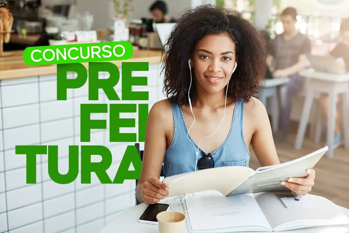 Candidata estuda para concurso público da Prefeitura de Mombuca SP com livro aberto e fone de ouvido