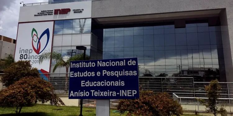 Fachada do edifício sede do Instituto Nacional de Estudos e Pesquisas Educacionais Anísio Teixeira, o INEP, com placa de identificação institucional em azul e branco em primeiro plano e painel comemorativo dos 80 anos do instituto ao fundo, órgão responsável pela organização do Encceja 2026