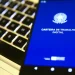 Smartphone exibindo a tela inicial do aplicativo Carteira de Trabalho Digital sobre teclado de notebook, representando o mercado de trabalho em 2026