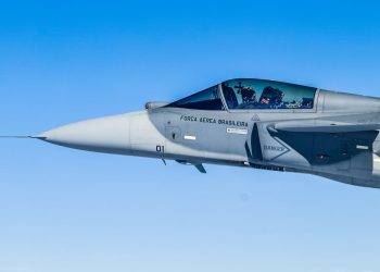 Piloto dentro de caça supersônico da Força Aérea Brasileira em voo sob céu azul