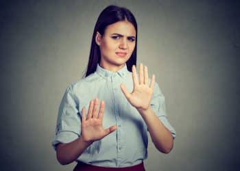 Mulher com expressão de desagrado e mãos levantadas em sinal de recusa, representando insegurança nas interações sociais.