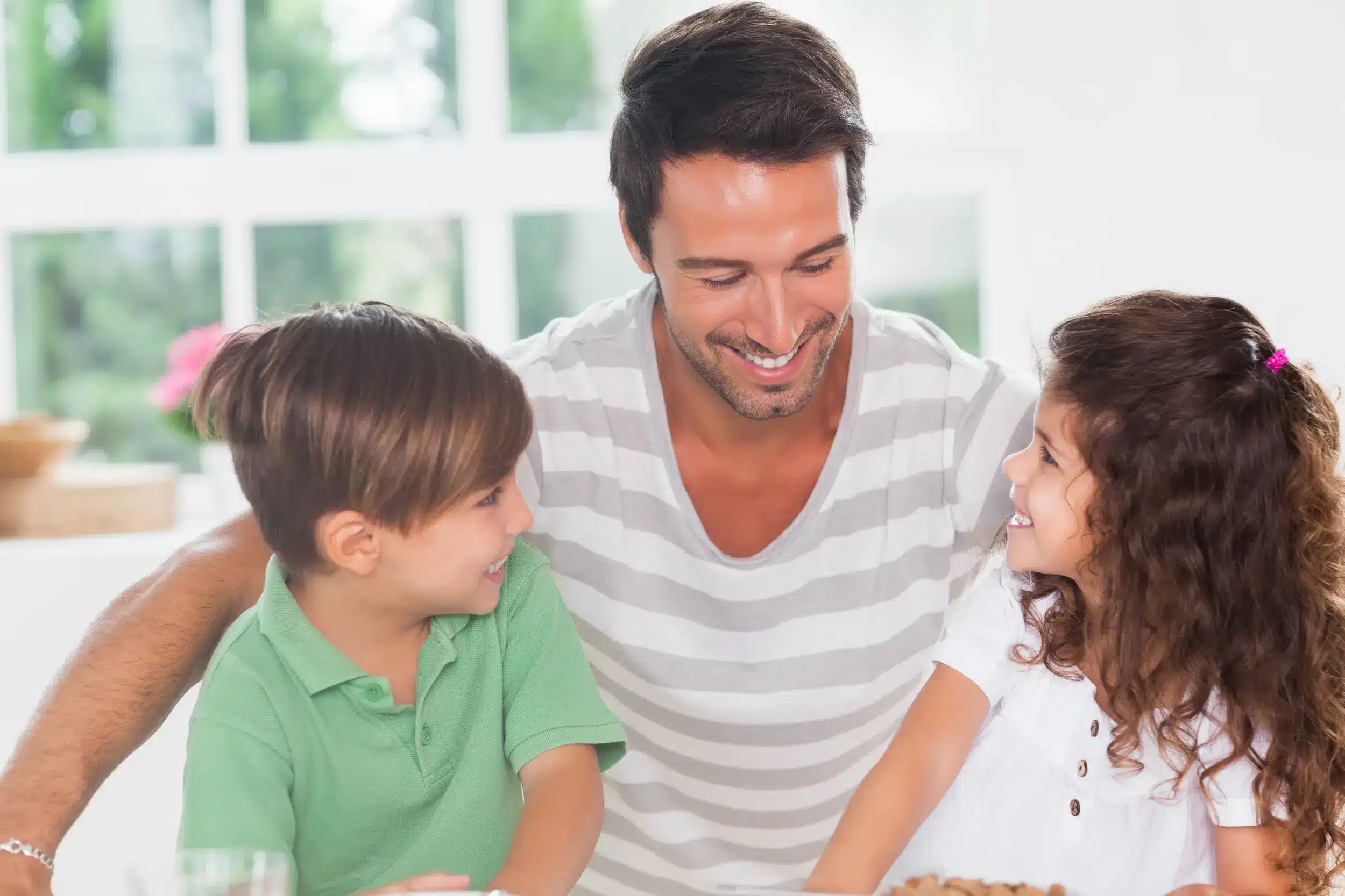 Pai sorrindo e brincando com seus filhos, refletindo sobre os efeitos do tratamento desigual entre irmãos.