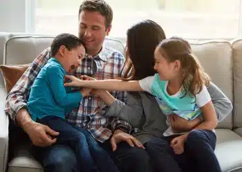 Família brincando juntos no sofá, representando os comportamentos comuns em adultos que foram o filho favorito durante a infância.