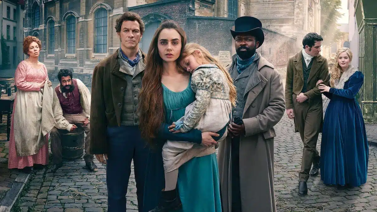 Personagens de 'Os Miseráveis' em uma cena do filme, com Jean Valjean (Hugh Jackman) no centro, acompanhado por outros personagens do clássico de Victor Hugo.