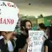 Manifestantes segurando cartazes em protesto contra a escala 6x1, com faixas escritas "Escala 6x1 é desumano" e "Quem quer que você trabalhe 6x1 trabalha 3x4"