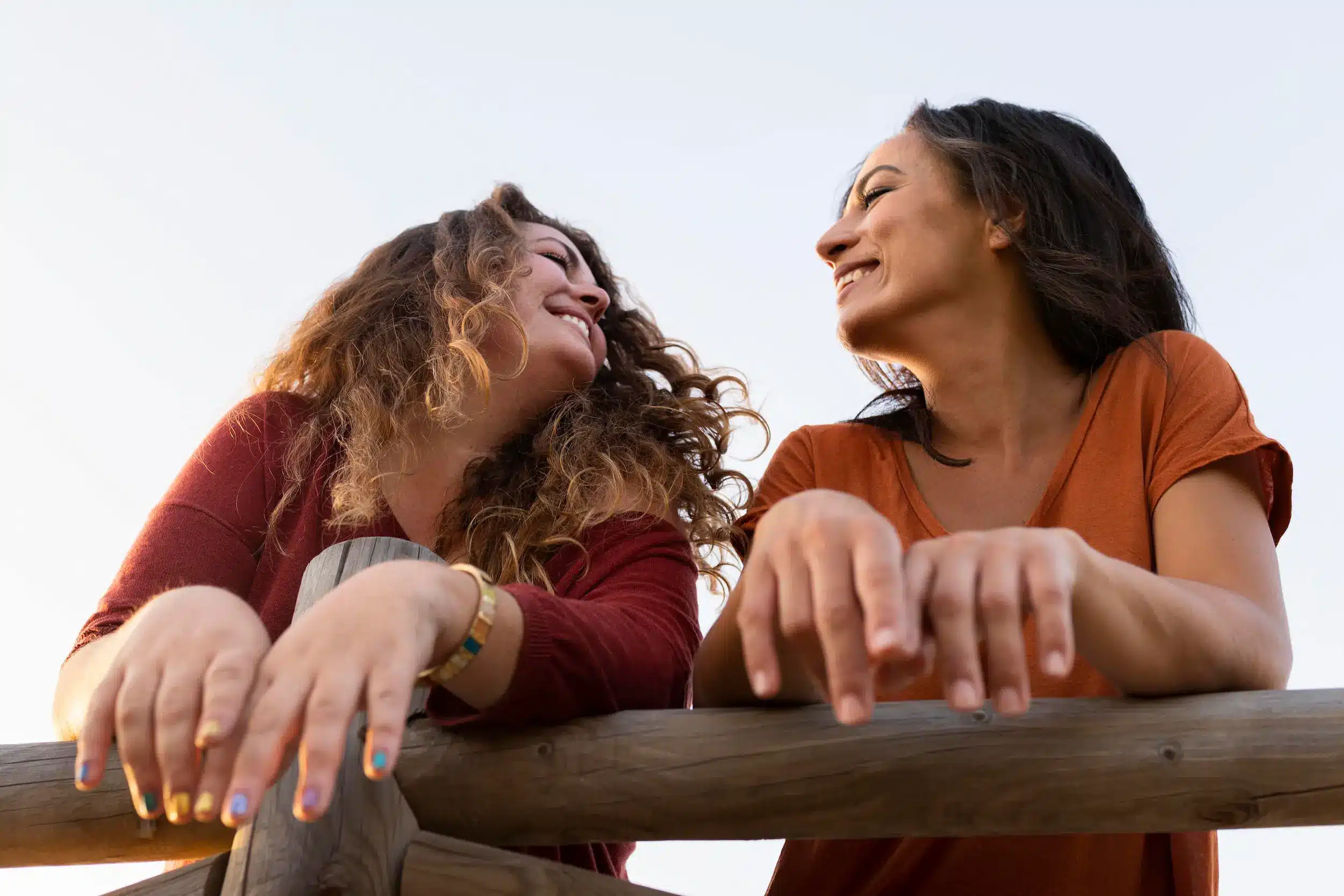 Duas amigas sorrindo e conversando ao ar livre representando a importância dos relacionamentos para o bem-estar emocional.