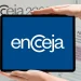 Imagem do logotipo do Encceja 2026, com fundo azul e mãos segurando um tablet mostrando o logo, destacando a importância da inscrição para o exame.