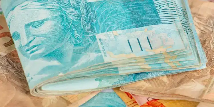 Notas de dinheiro coloridas com destaque para a cédula de 100 reais em azul, representando o tema de pagamentos de março do INSS.