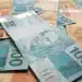 Notas de real em destaque, incluindo cédulas de 100 e 50 reais, ilustrando os pagamentos do INSS de março de 2026.