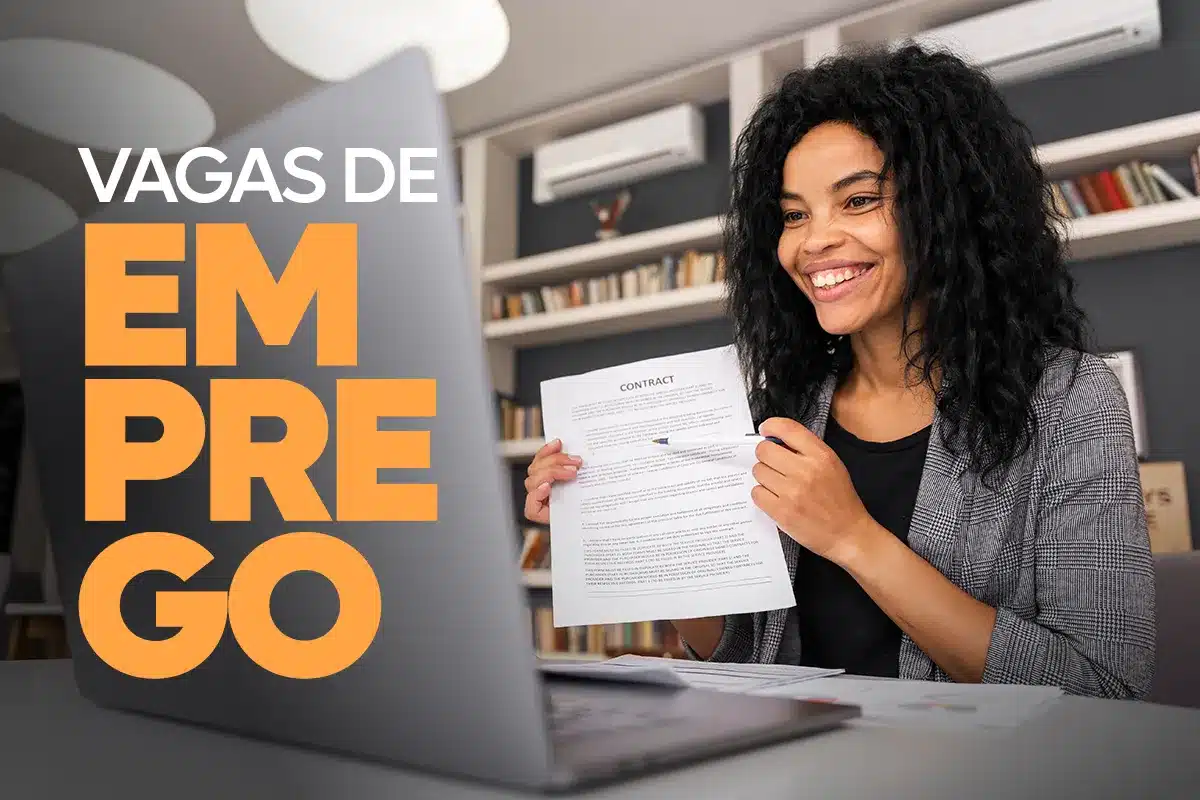 Mulher negra de cabelos cacheados sorrindo e segurando um contrato de trabalho em frente a um notebook, com o texto "VAGAS DE EMPREGO" em destaque nas cores branco e laranja.